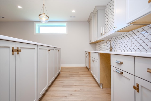 16217 Walnut Meadows Ct, Urbandale, IA 50323 - kitchen featuring light wood finished floors, light countertops, decorative backsplash, baseboards, and hanging light fixtures