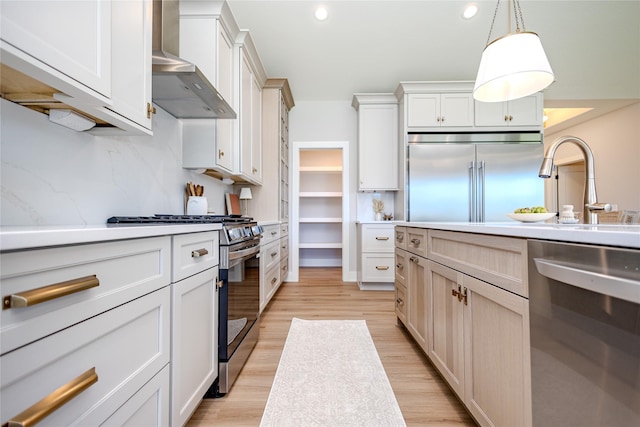 16217 Walnut Meadows Ct, Urbandale, IA 50323 - kitchen with stainless steel appliances, wall chimney exhaust hood, light countertops, light wood-style flooring, and pendant lighting