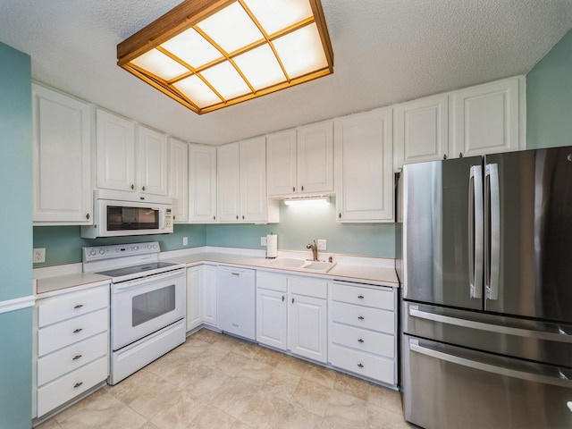 kitchen with white appliances, sink, a textured ceiling, and white cabinets