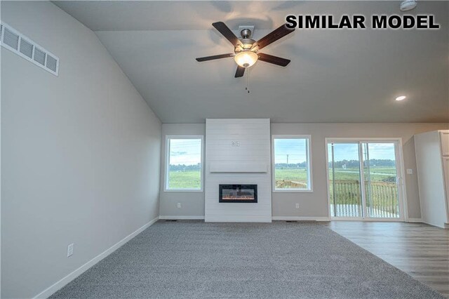 unfurnished living room featuring ceiling fan, lofted ceiling, carpet floors, and a fireplace