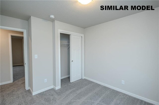 unfurnished bedroom with carpet floors, a textured ceiling, and a closet