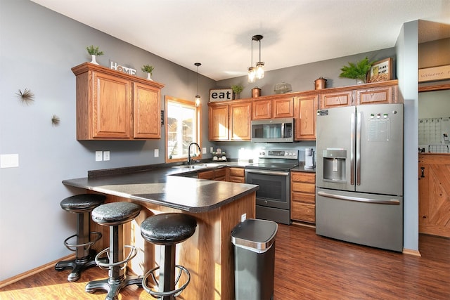 kitchen featuring dark hardwood / wood-style flooring, hanging light fixtures, stainless steel appliances, and sink