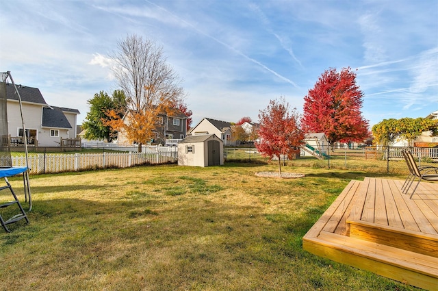 view of yard with a wooden deck, a playground, and a shed