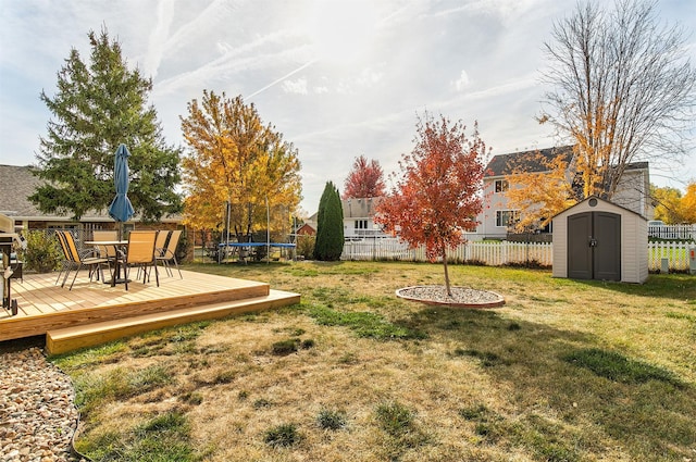 view of yard with a wooden deck, a trampoline, and a storage unit