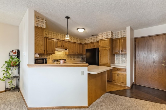 kitchen featuring pendant lighting, light carpet, black appliances, and kitchen peninsula