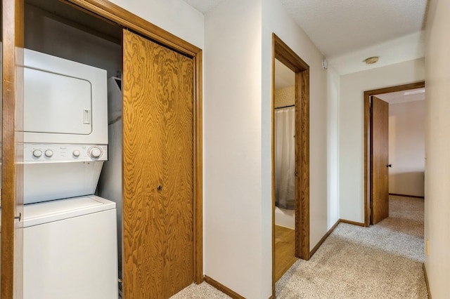 clothes washing area with stacked washing maching and dryer and light carpet