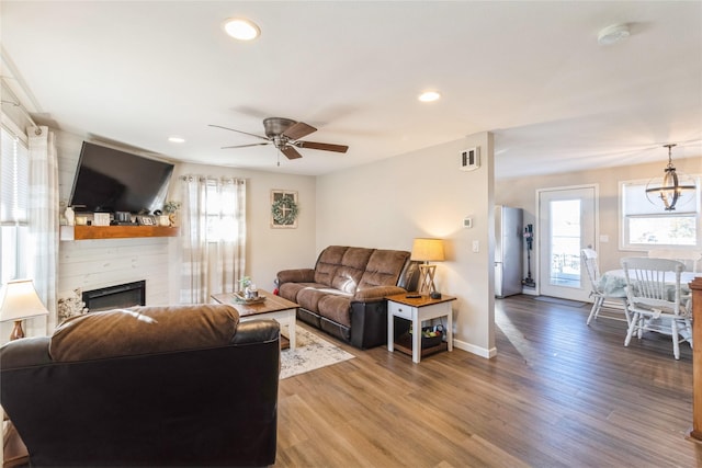 living room featuring a large fireplace, hardwood / wood-style floors, and ceiling fan