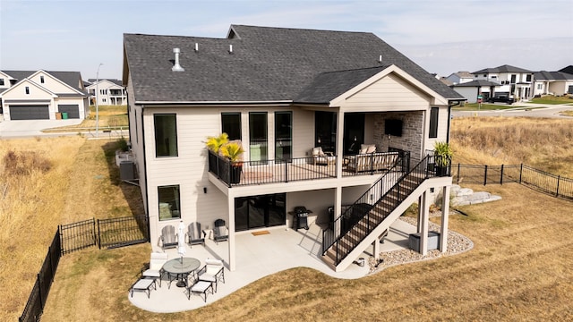 rear view of house with stairs, roof with shingles, a patio area, and a fenced backyard