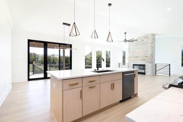 kitchen featuring pendant lighting, sink, a kitchen island with sink, a healthy amount of sunlight, and light brown cabinets