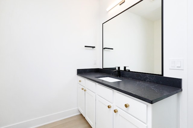 bathroom featuring vanity, baseboards, and wood finished floors