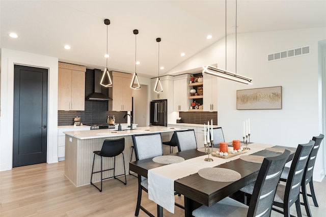 dining space with vaulted ceiling, light wood-style flooring, visible vents, and recessed lighting