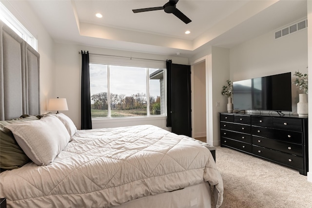 carpeted bedroom with a ceiling fan, a tray ceiling, visible vents, and recessed lighting