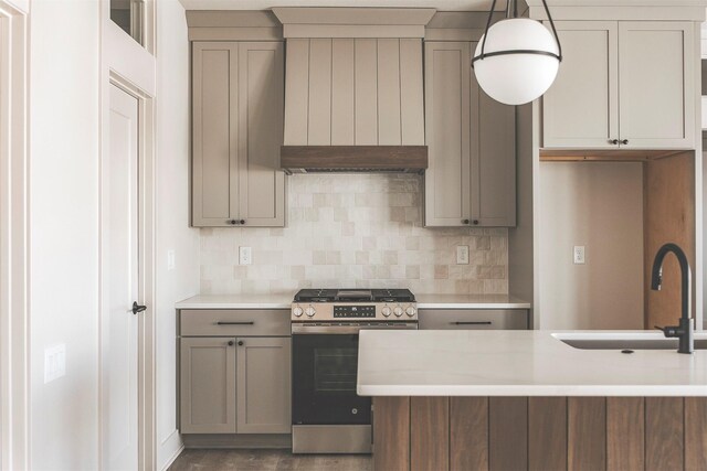 kitchen featuring gas range, ventilation hood, sink, tasteful backsplash, and pendant lighting