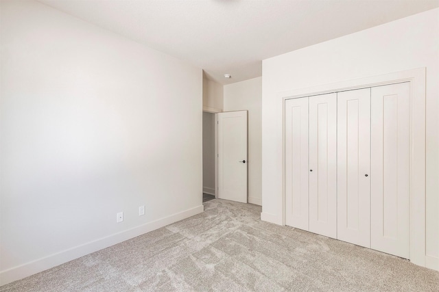 unfurnished bedroom with light carpet and a closet