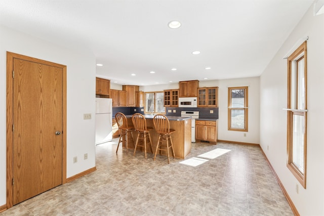 kitchen with white appliances, plenty of natural light, a kitchen breakfast bar, and a center island