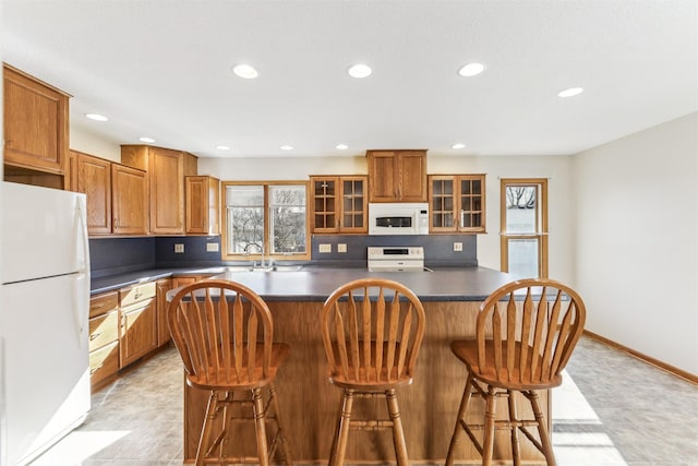 kitchen featuring white appliances, a kitchen island, and a breakfast bar area