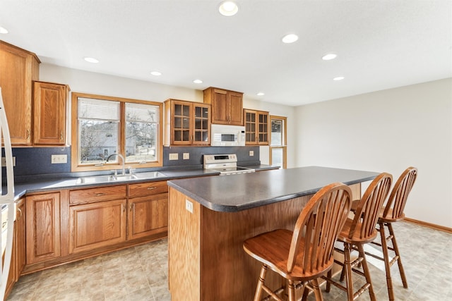 kitchen featuring sink, a breakfast bar area, a center island, decorative backsplash, and stainless steel range with electric cooktop