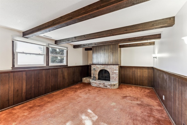 unfurnished living room with beamed ceiling, a brick fireplace, carpet floors, and wood walls