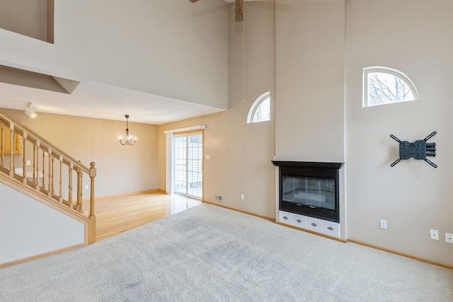 unfurnished living room featuring light carpet, a notable chandelier, a towering ceiling, and a multi sided fireplace