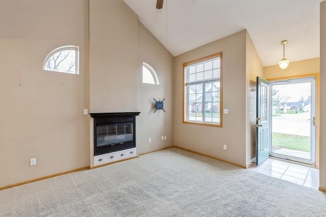 unfurnished living room featuring light carpet, high vaulted ceiling, ceiling fan, and a multi sided fireplace