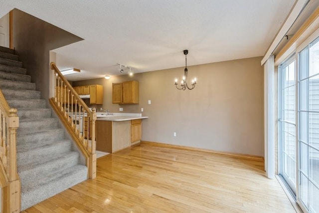 kitchen with hanging light fixtures, kitchen peninsula, a chandelier, and light hardwood / wood-style flooring