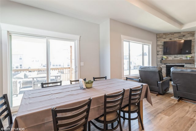 dining space featuring a fireplace, light hardwood / wood-style floors, and a healthy amount of sunlight