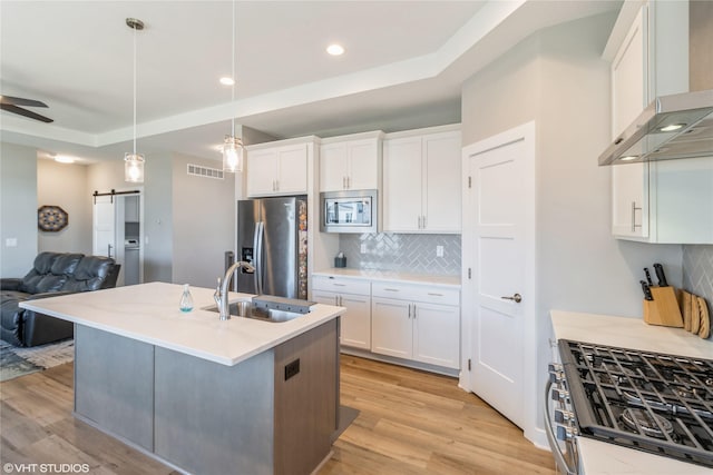 1210 NW Pine Bluff Cir, Waukee, IA 50263 - kitchen featuring stainless steel appliances, extractor fan, light wood finished floors, open floor plan, and recessed lighting