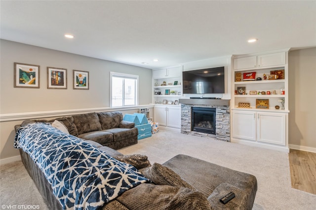 living room featuring built in shelves, light colored carpet, and a fireplace