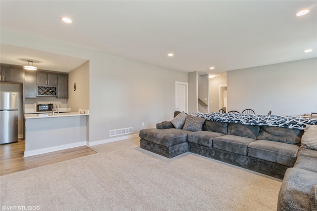 living room featuring light colored carpet and sink