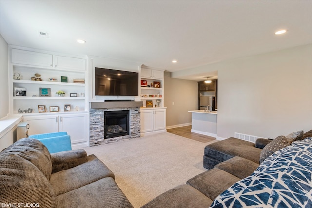 carpeted living room featuring a stone fireplace