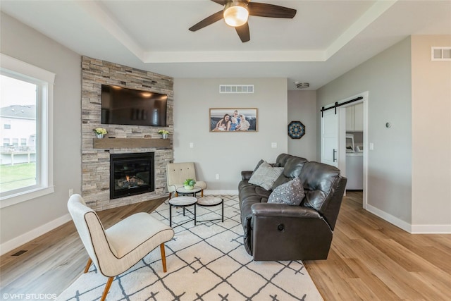 1210 NW Pine Bluff Cir, Waukee, IA 50263 - living room with a ceiling fan, a raised ceiling, wood finished floors, and a barn door