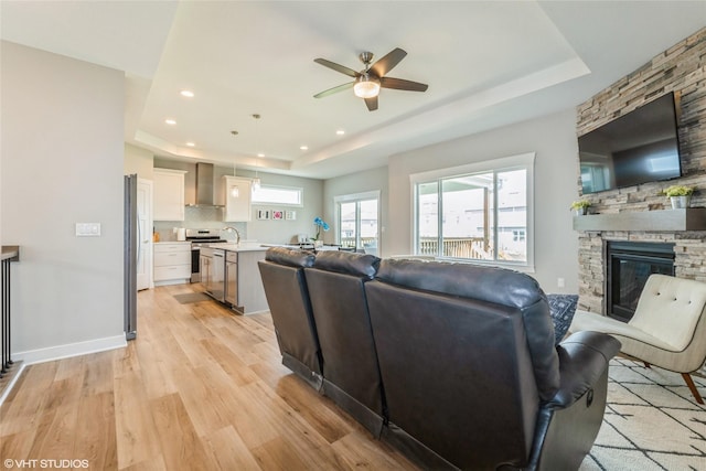 1210 NW Pine Bluff Cir, Waukee, IA 50263 - living room with a raised ceiling, a ceiling fan, light wood finished floors, a fireplace, and recessed lighting