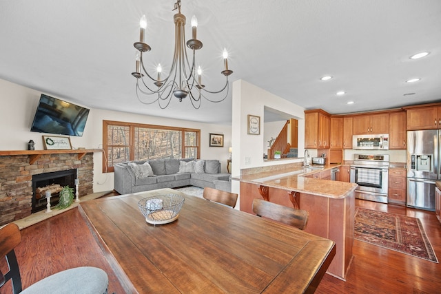 dining room featuring sink, an inviting chandelier, a fireplace, and dark hardwood / wood-style flooring