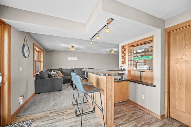 kitchen with a kitchen bar, light brown cabinetry, kitchen peninsula, and light hardwood / wood-style flooring