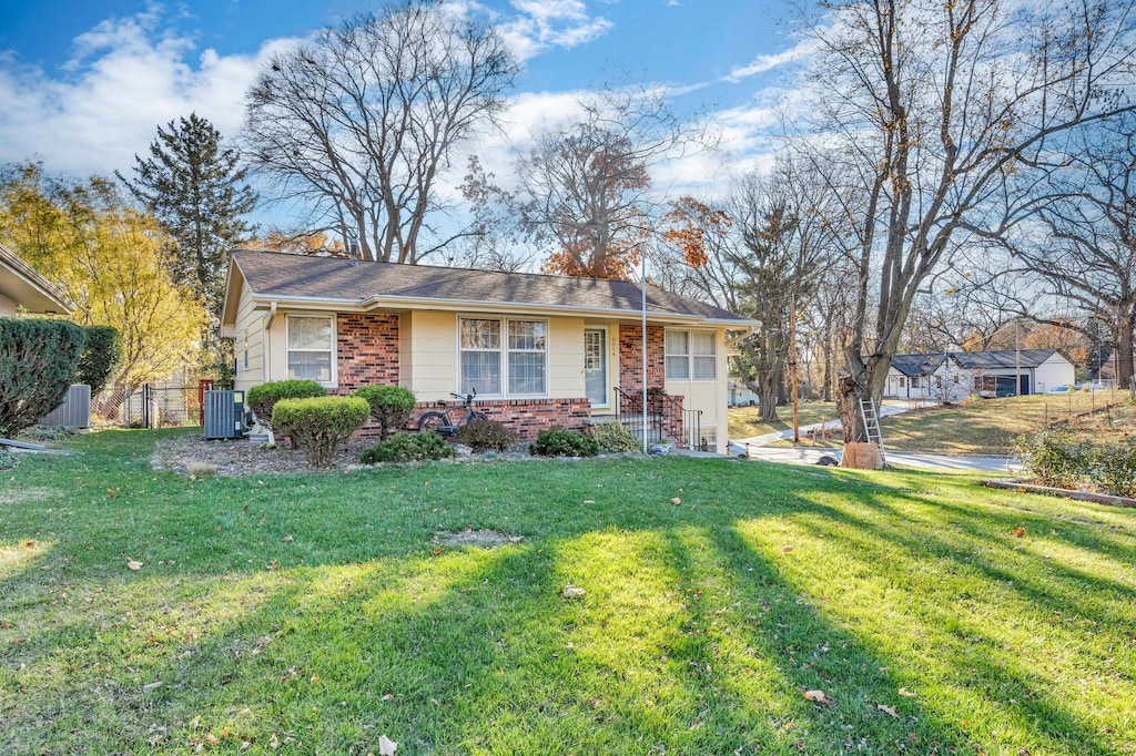 single story home with central AC unit and a front yard