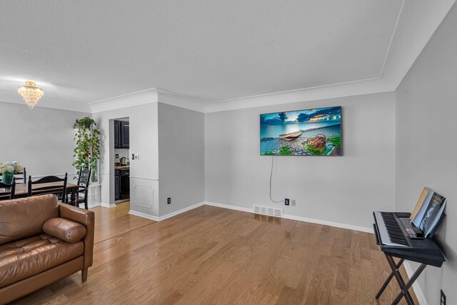 living area featuring ornamental molding, hardwood / wood-style floors, and a notable chandelier