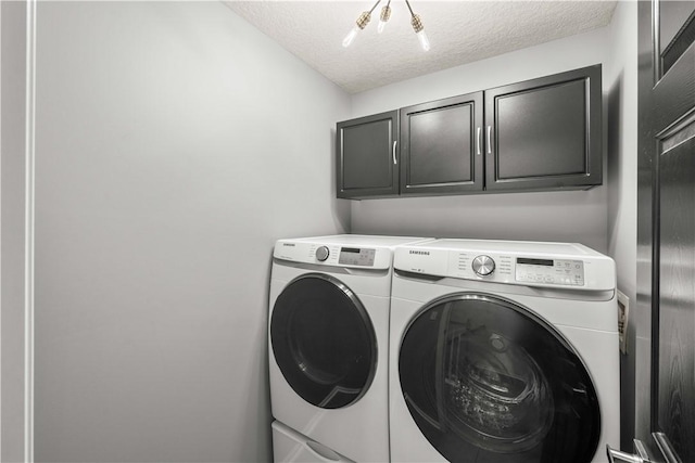 washroom featuring cabinets, washer and dryer, and a textured ceiling