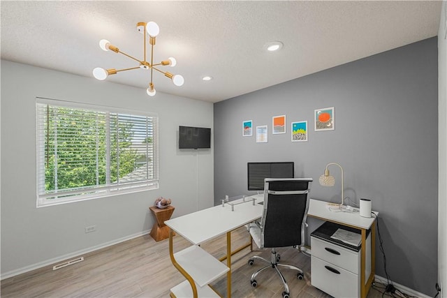 home office with a textured ceiling, an inviting chandelier, and light hardwood / wood-style flooring