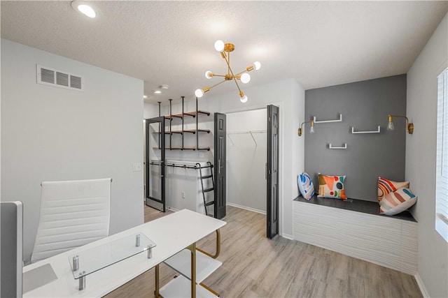 office space featuring light hardwood / wood-style floors, a textured ceiling, and a notable chandelier