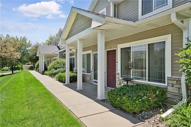 doorway to property featuring a porch and a lawn