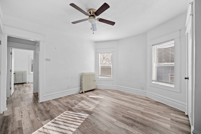 interior space featuring ceiling fan, radiator heating unit, a textured ceiling, and light hardwood / wood-style floors