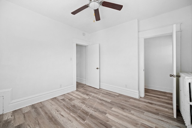 unfurnished bedroom featuring ceiling fan, radiator heating unit, light hardwood / wood-style floors, and a closet