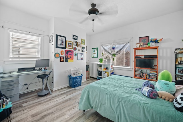 bedroom with multiple windows, radiator heating unit, ceiling fan, and light hardwood / wood-style flooring