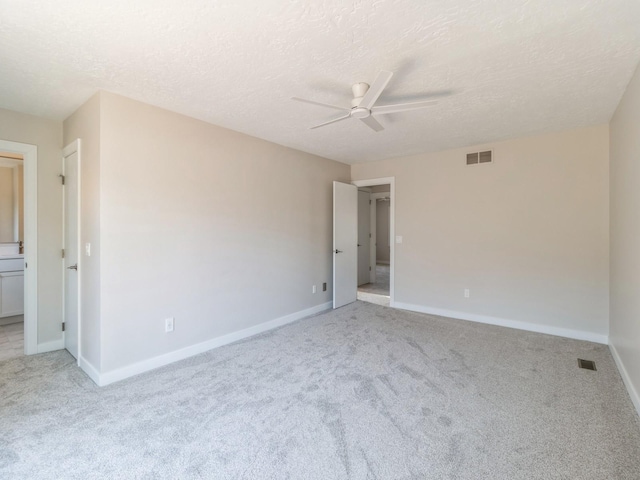 spare room featuring a textured ceiling, light colored carpet, and ceiling fan