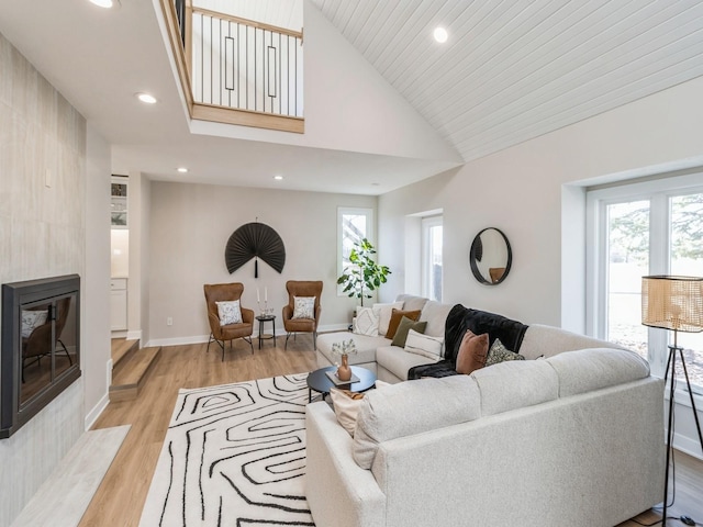 living room featuring a fireplace, high vaulted ceiling, and light wood-type flooring