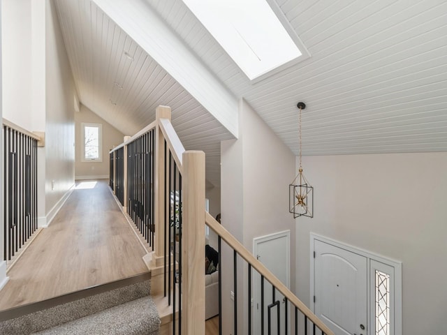 hall with hardwood / wood-style flooring, high vaulted ceiling, and a skylight