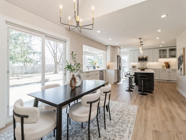 dining room featuring sink, a chandelier, and light wood-type flooring