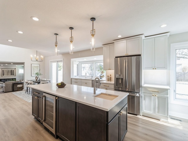 kitchen featuring pendant lighting, white cabinetry, sink, stainless steel fridge, and beverage cooler