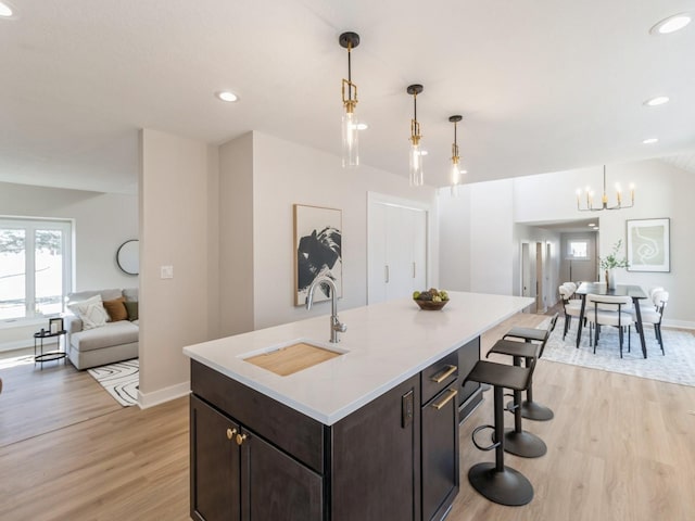 kitchen with pendant lighting, sink, a kitchen island with sink, and light hardwood / wood-style floors