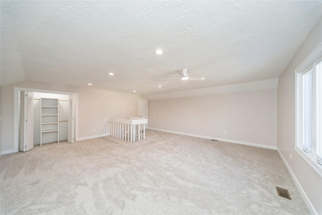 spare room with light colored carpet, plenty of natural light, and a textured ceiling